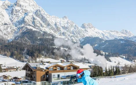 Super Snow Deal Skier carving on groomed slope with snowy Alpine mountains and chalets in background